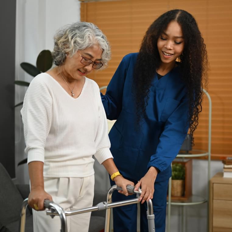 Caregiver assisting an elderly woman with a walker.