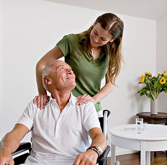 A caregiver assisting an elderly man in a room.