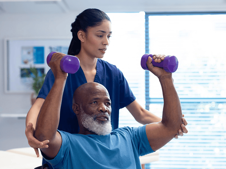 Staff assisting a resident with weights in therapy
