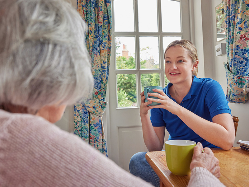 Staff member interacting with resident over coffee.