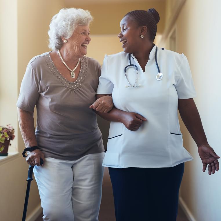Nurse assisting an elderly resident in a hallway.