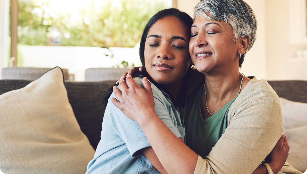Two women embracing on a couch.