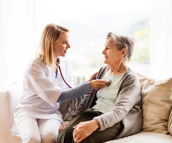 Nurse checking elderly woman's heartbeat