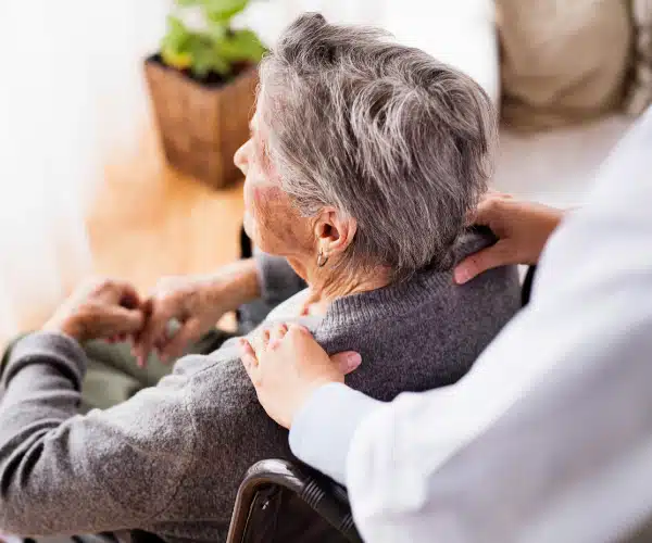 Caregiver assisting an elderly woman in a cozy setting.