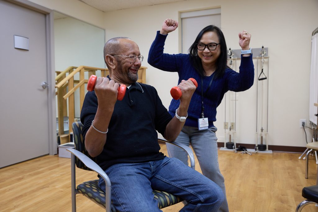Senior exercising with staff encouragement