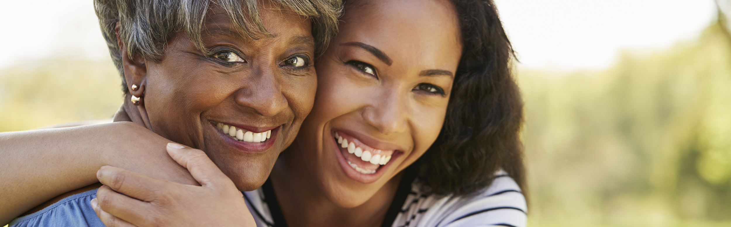 Two women smiling and embracing outdoors.