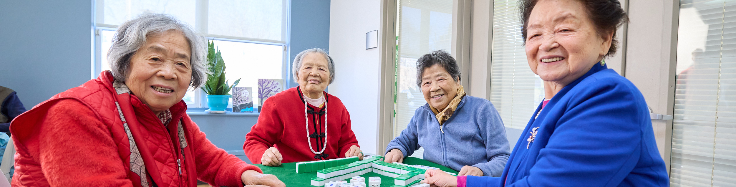 Four elderly women playing a game indoors.