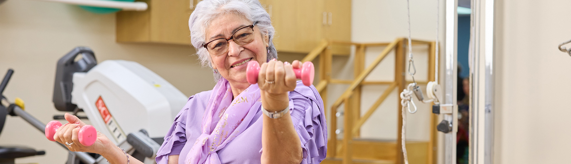 Senior woman exercising with weights in therapy session.