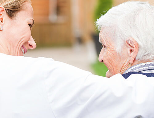 Caregiver embracing a senior resident outdoors.
