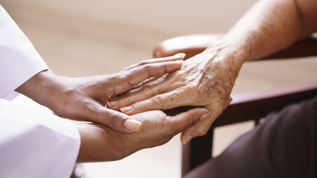 Caregiver holding elderly person's hand
