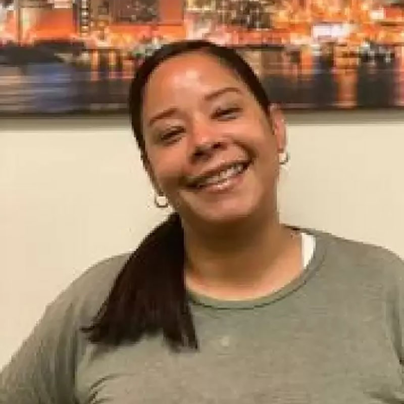Smiling staff member in front of a cityscape photo.
