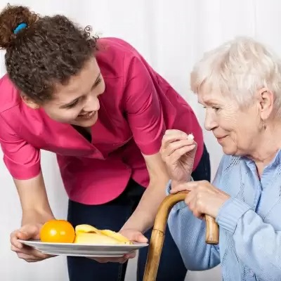 Caregiver serving food to a senior resident