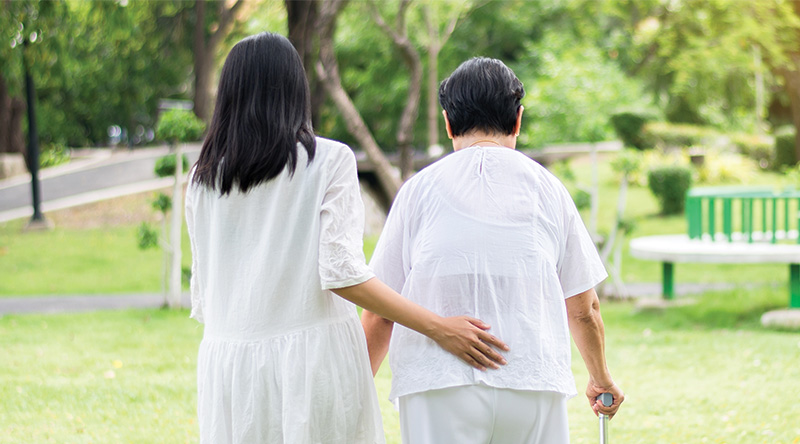 Caregiver assisting elderly woman in a park