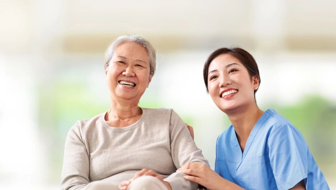 Senior resident and staff member smiling together