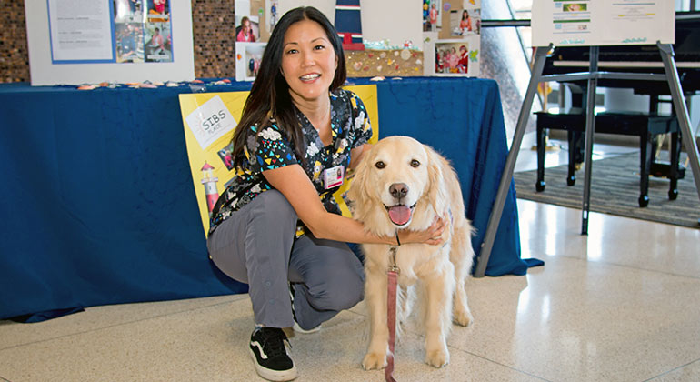 Staff member with therapy dog in a common area.