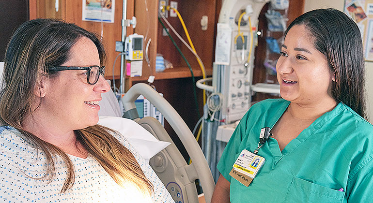 Nurse and patient smiling in a hospital room.