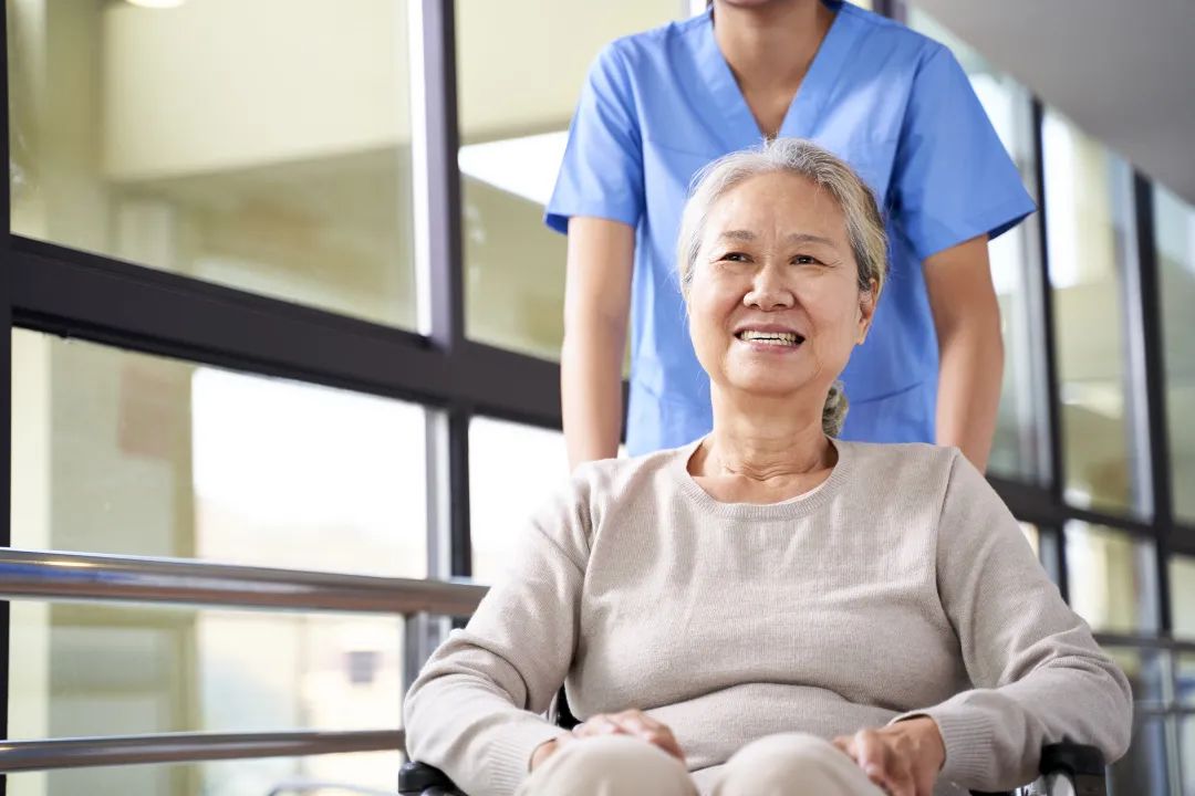 Senior woman smiling in a wheelchair with caregiver