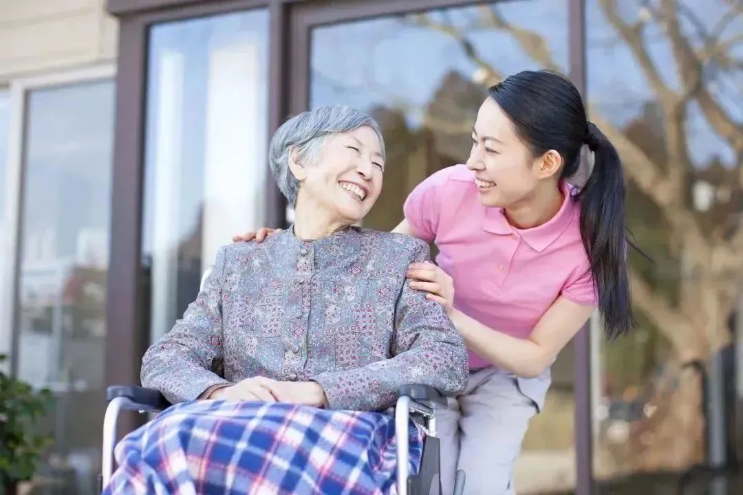 Caregiver and resident enjoying a sunny moment outdoors.
