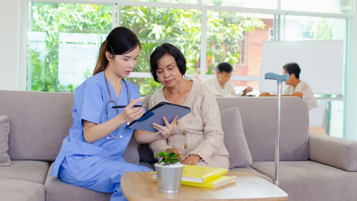 Caregiver assisting an elderly resident in a common area.