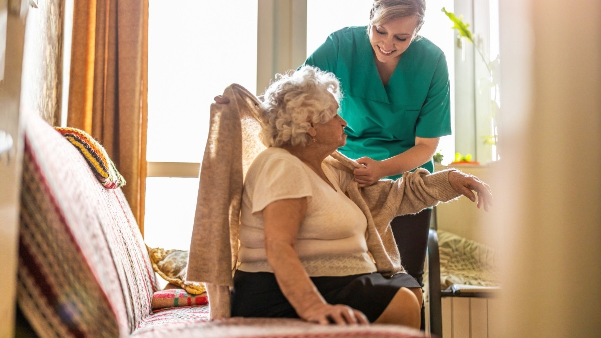 Caregiver assisting elderly resident in a cozy room
