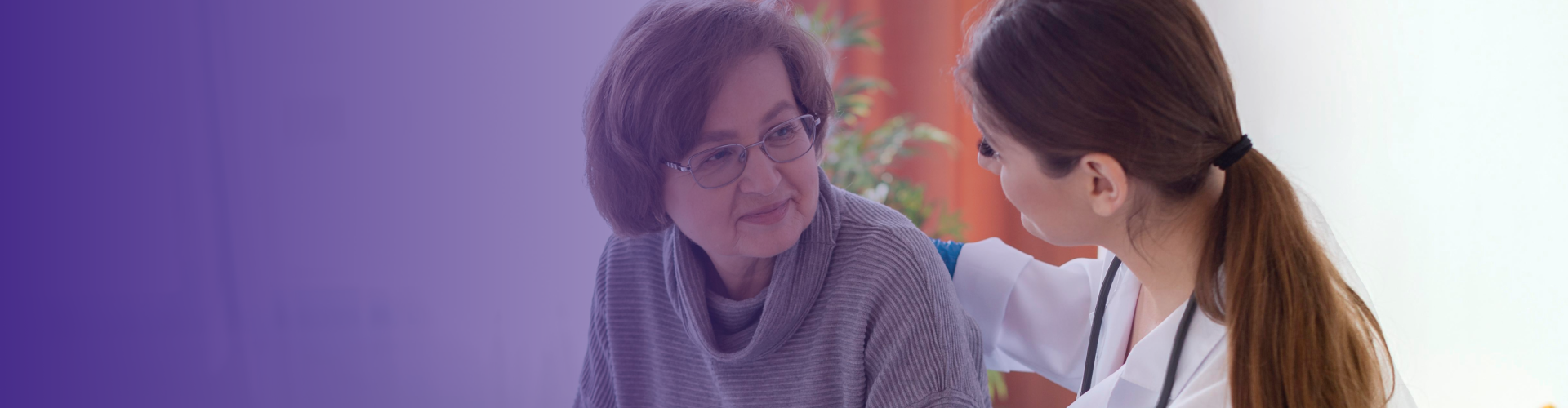 Senior resident interacting with staff member in a cozy setting.