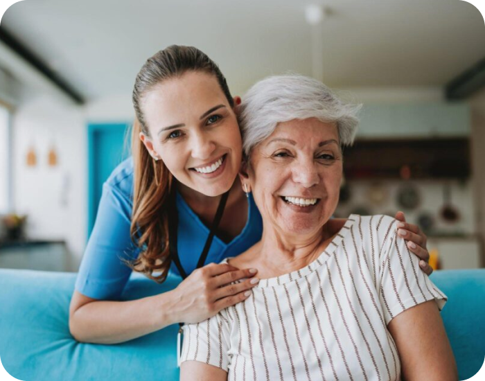 Caregiver and resident smiling together in a living room.