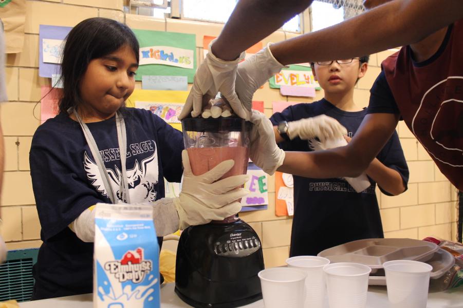 Children making smoothies together in a kitchen.