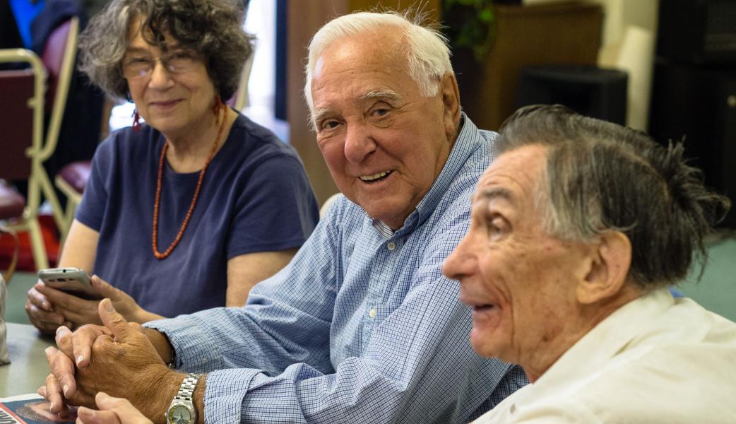 Three residents engaged in conversation indoors.