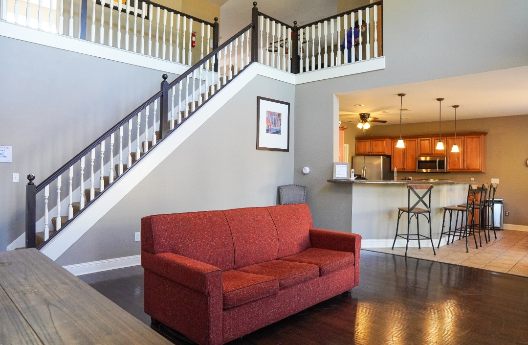 Common area with a red sofa and kitchen in background.