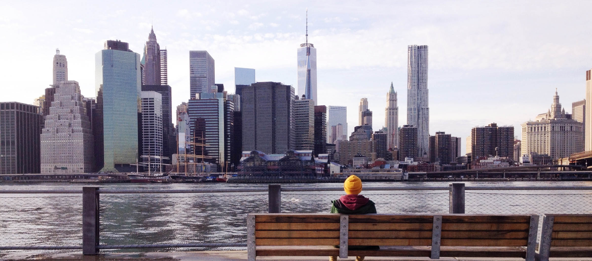 Person sitting on a bench overlooking a skyline.
