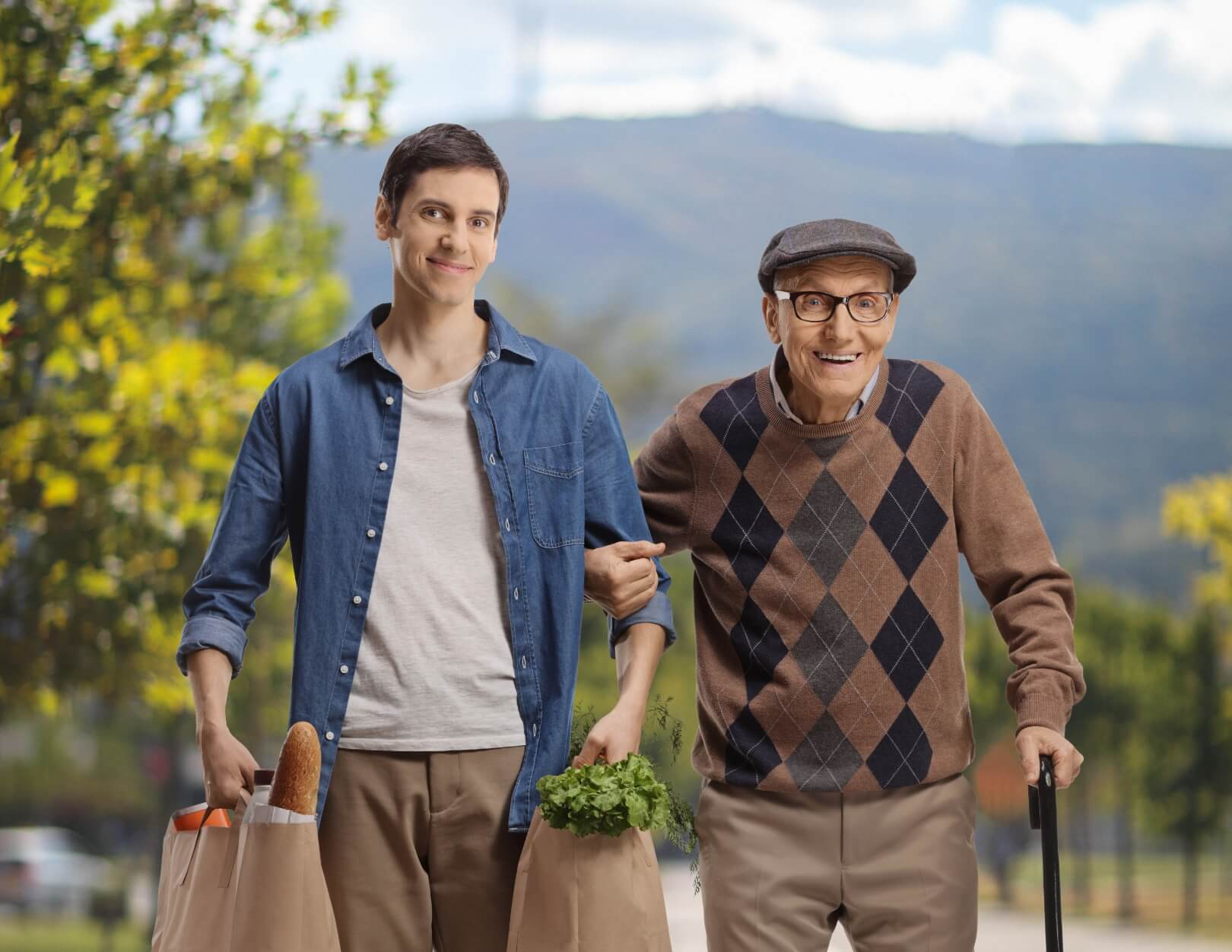 A young man walking with an elderly man outdoors.