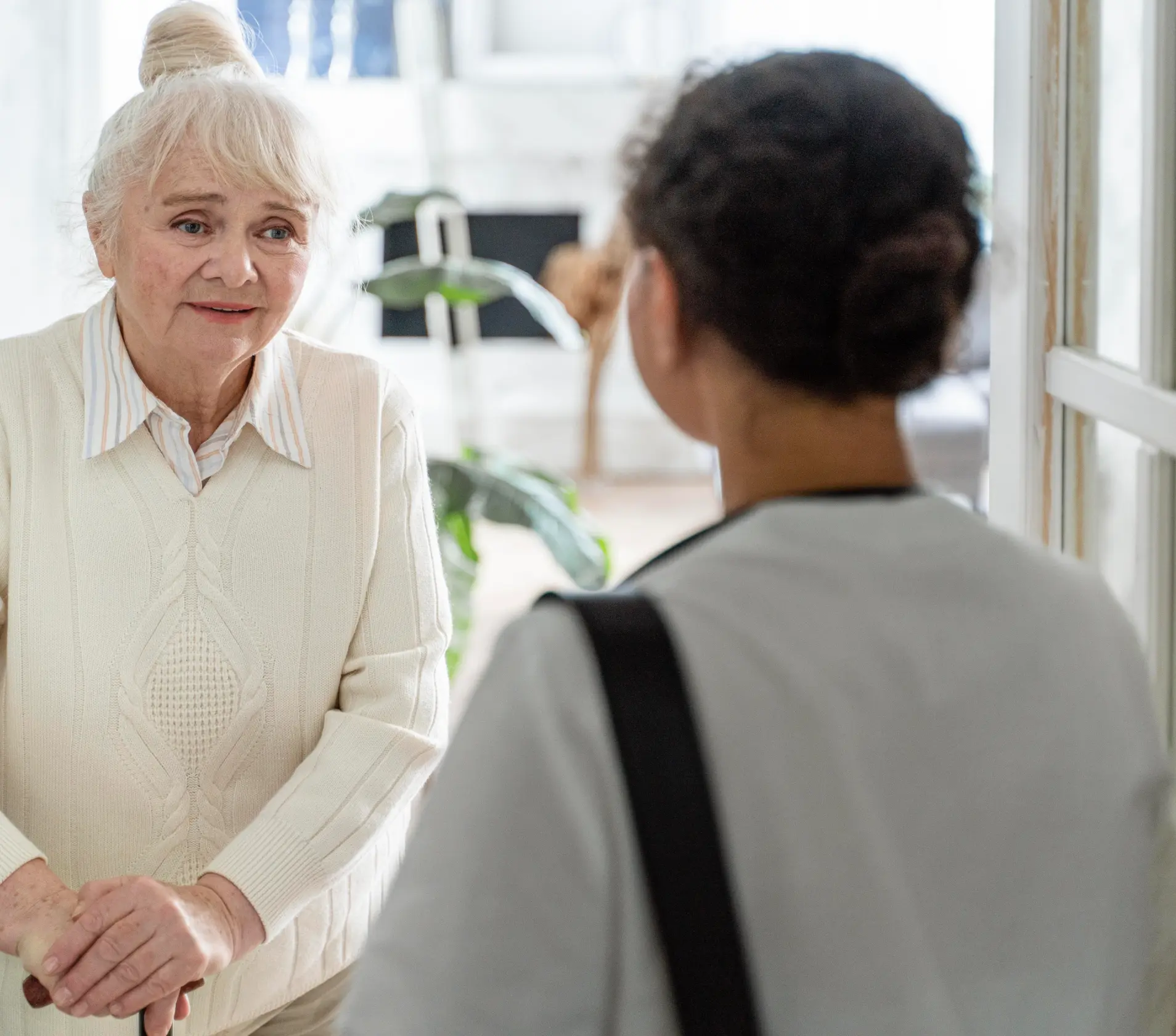 A senior woman talking with a caregiver indoors.