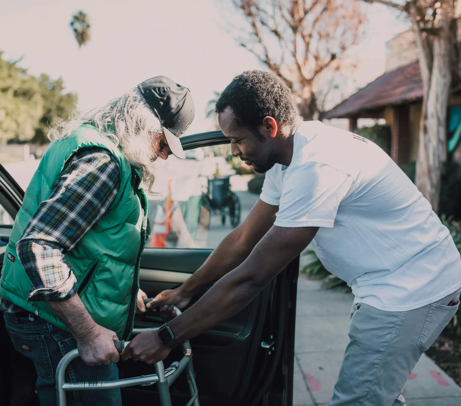 Staff assisting resident with a walker outside.