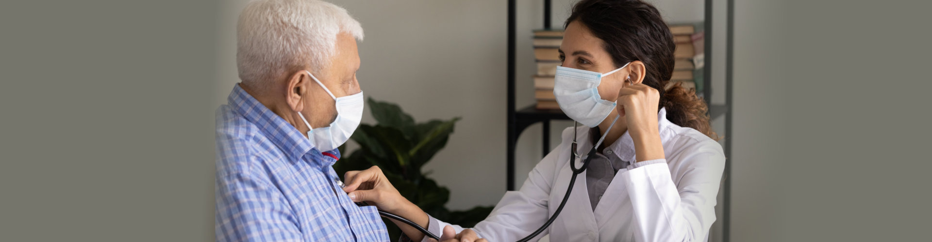 Healthcare professional checking elderly man's heartbeat.