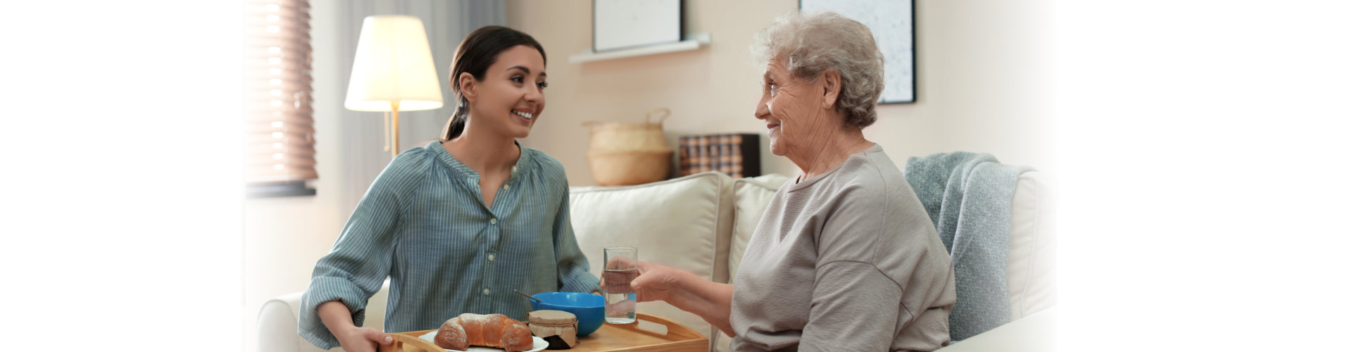Staff serving food to a resident in a cozy living area.