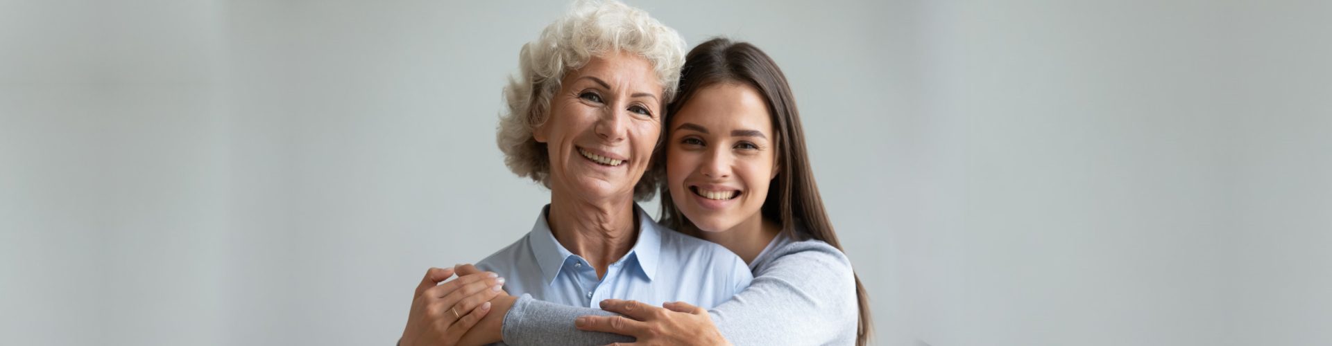 Smiling elderly woman hugging a younger woman
