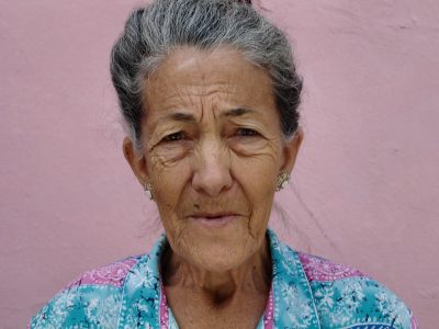 Portrait of an elderly woman with a pink background.