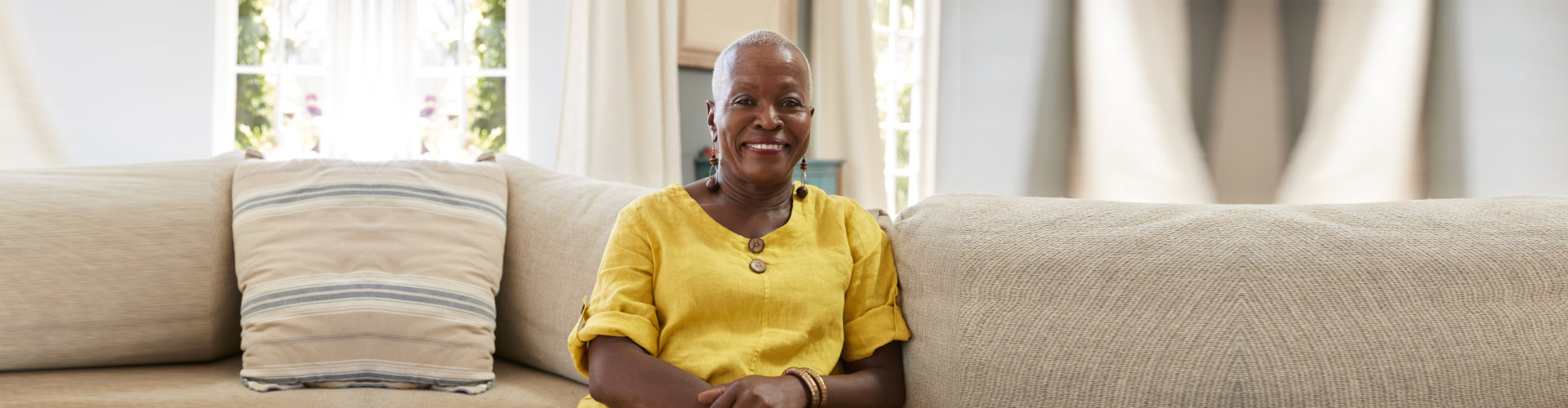 Smiling woman sitting on a couch in interior space.
