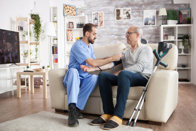 Caregiver checking a senior's blood pressure at home.