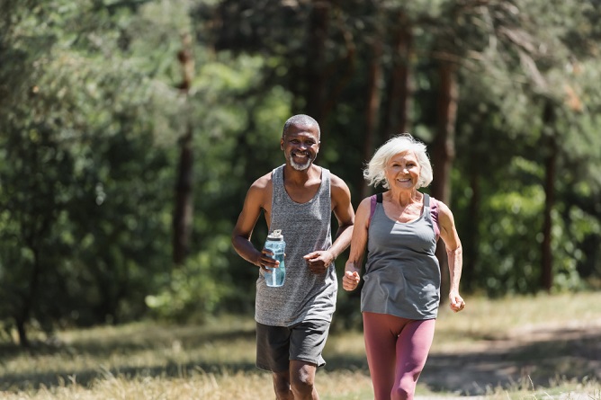 Two seniors jogging outdoors in a natural setting