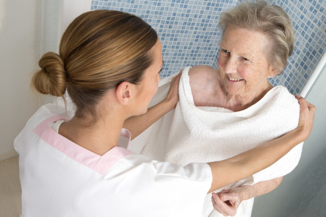 Caregiver assisting elderly woman in a spa setting.
