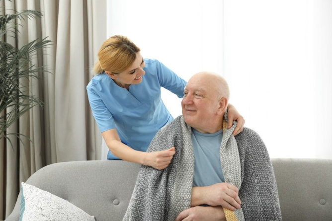 Caregiver assisting an elderly man in a cozy setting.