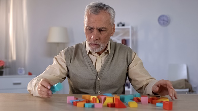 Senior man engaged in a creative activity with colorful blocks.