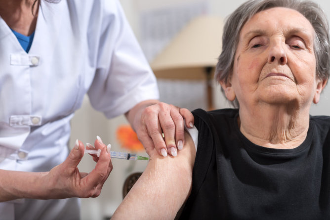 Nurse administering a vaccine to an elderly woman