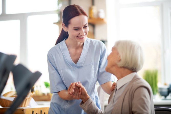 Healthcare worker assisting a senior resident indoors.