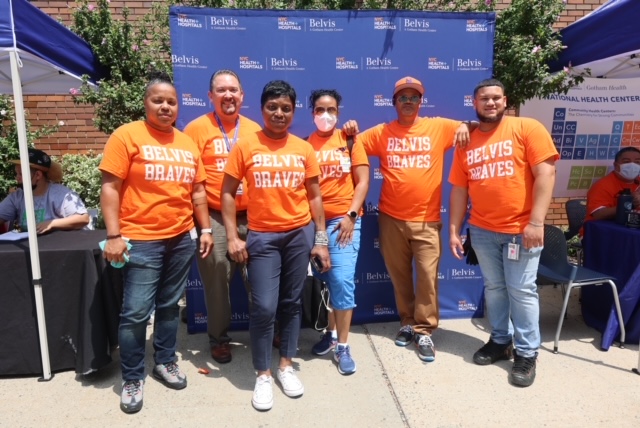 Group of staff members in orange shirts outdoors.