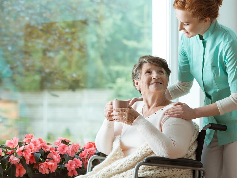 Caregiver assisting a smiling senior in a cozy setting.