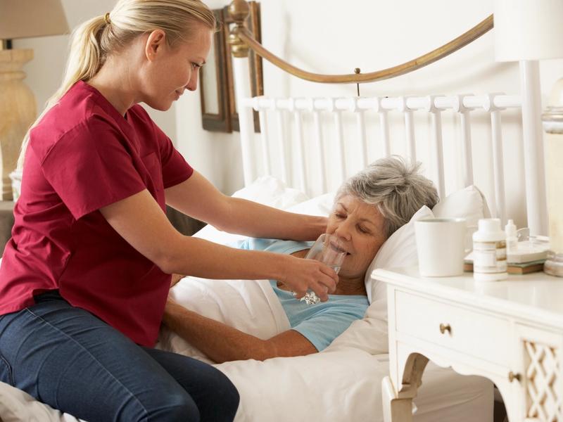 Nurse assisting senior woman with a glass of water