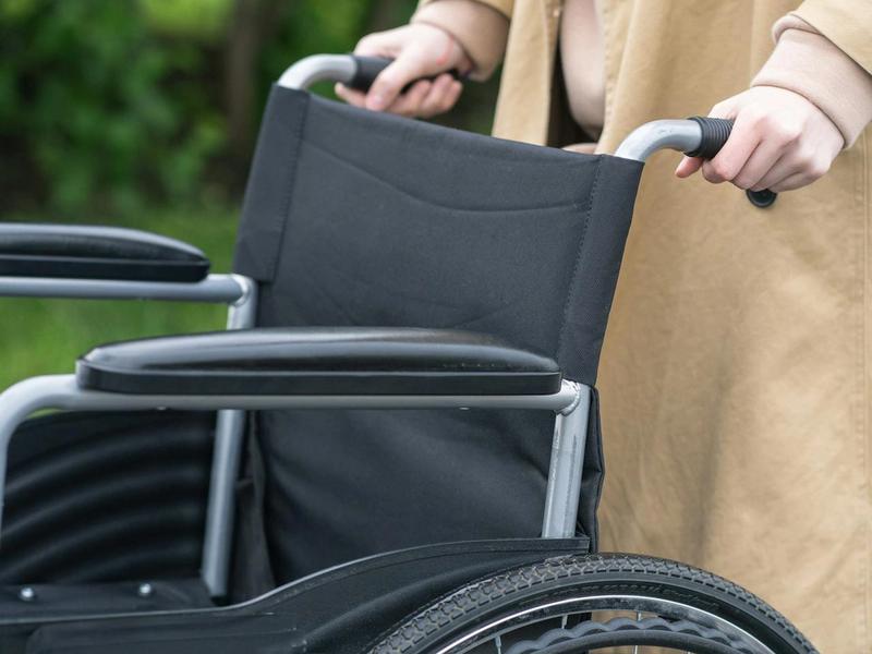 Person holding a wheelchair outdoors