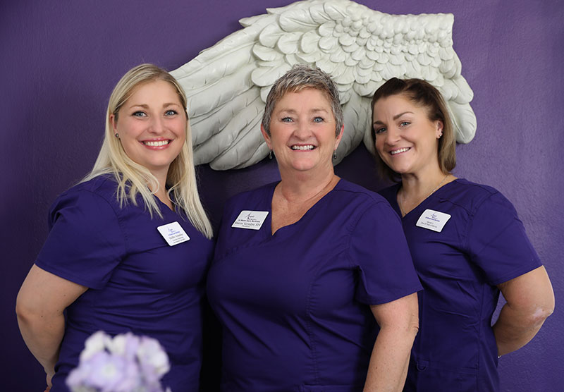 Three staff members smiling in scrubs